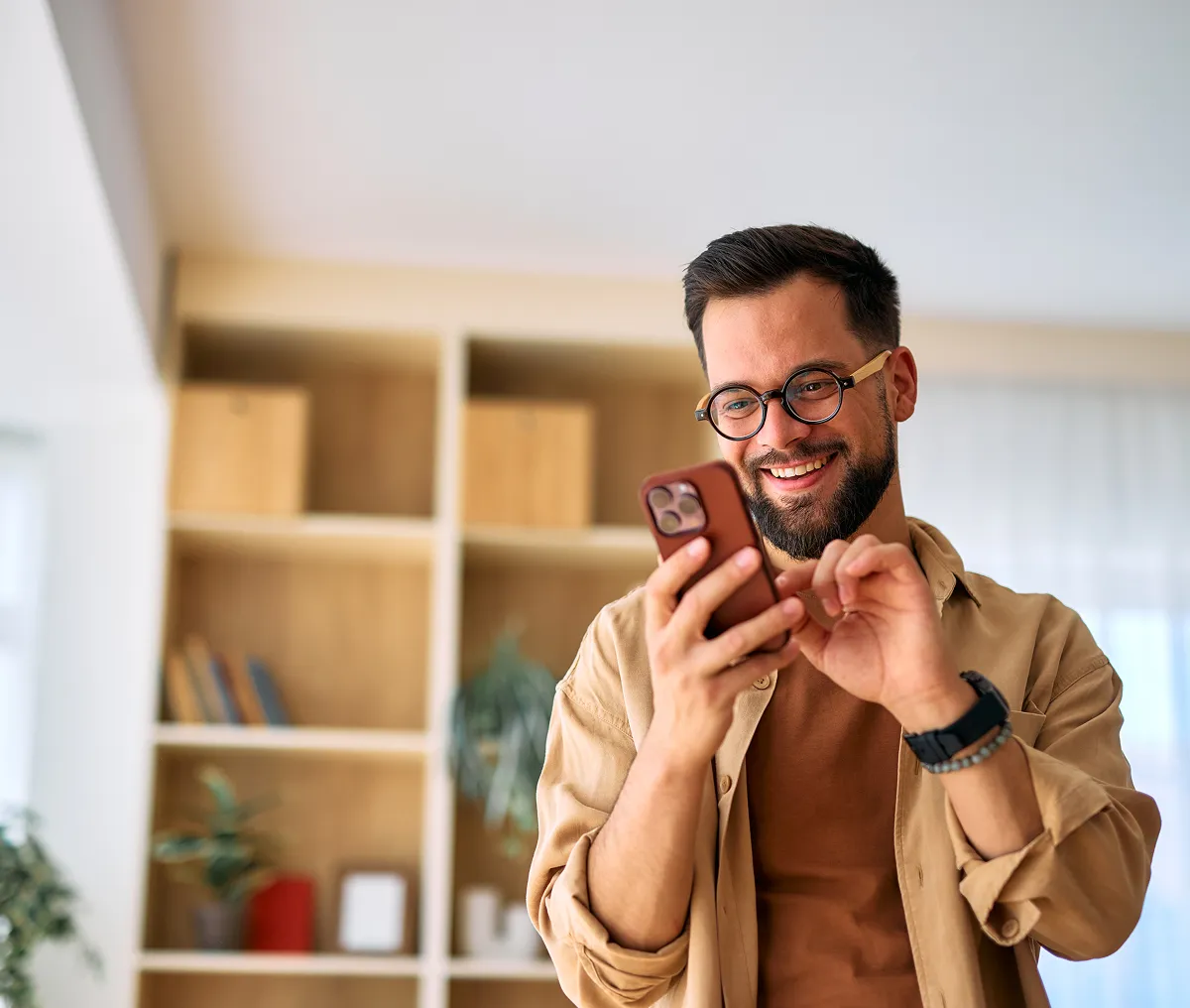 Man smiling and looking at his phone indoors.