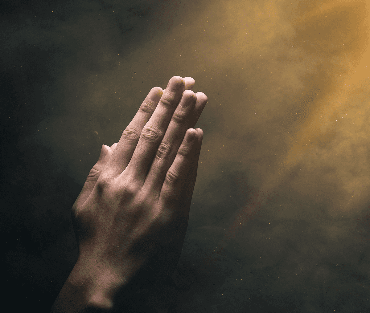 Hands joined together in prayer with a soft light background.