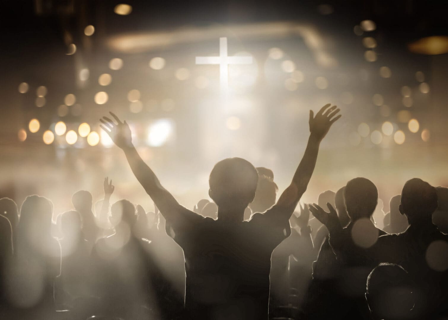 Person raising hands in worship for a glowing cross