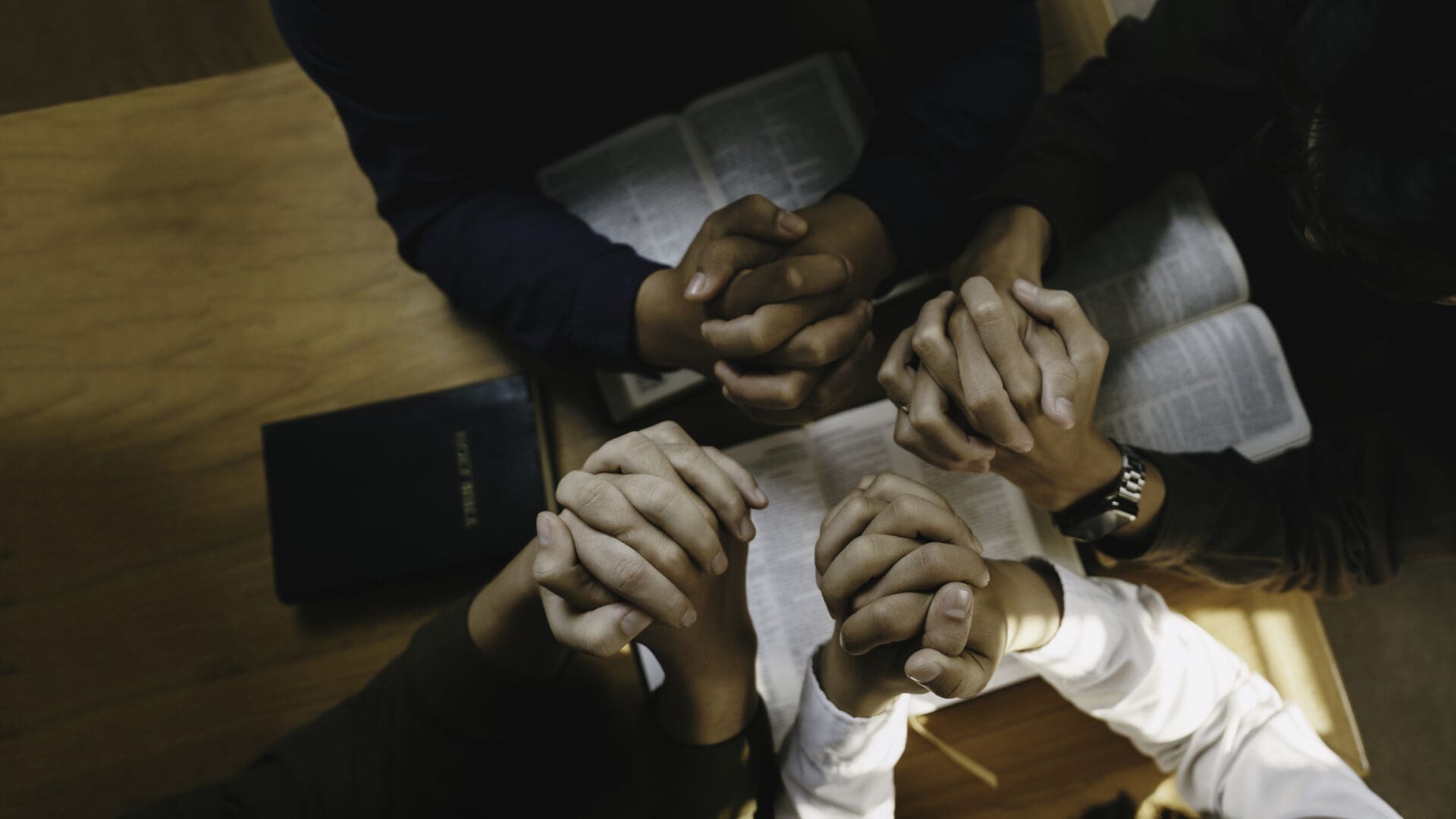 A group of people holding hands in a circle, symbolizing unity.