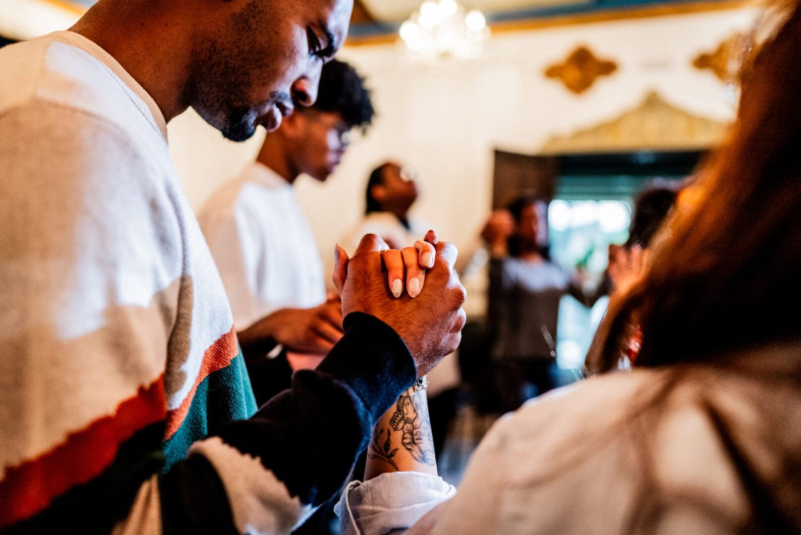 People holding hands in a moment of prayer or reflection.