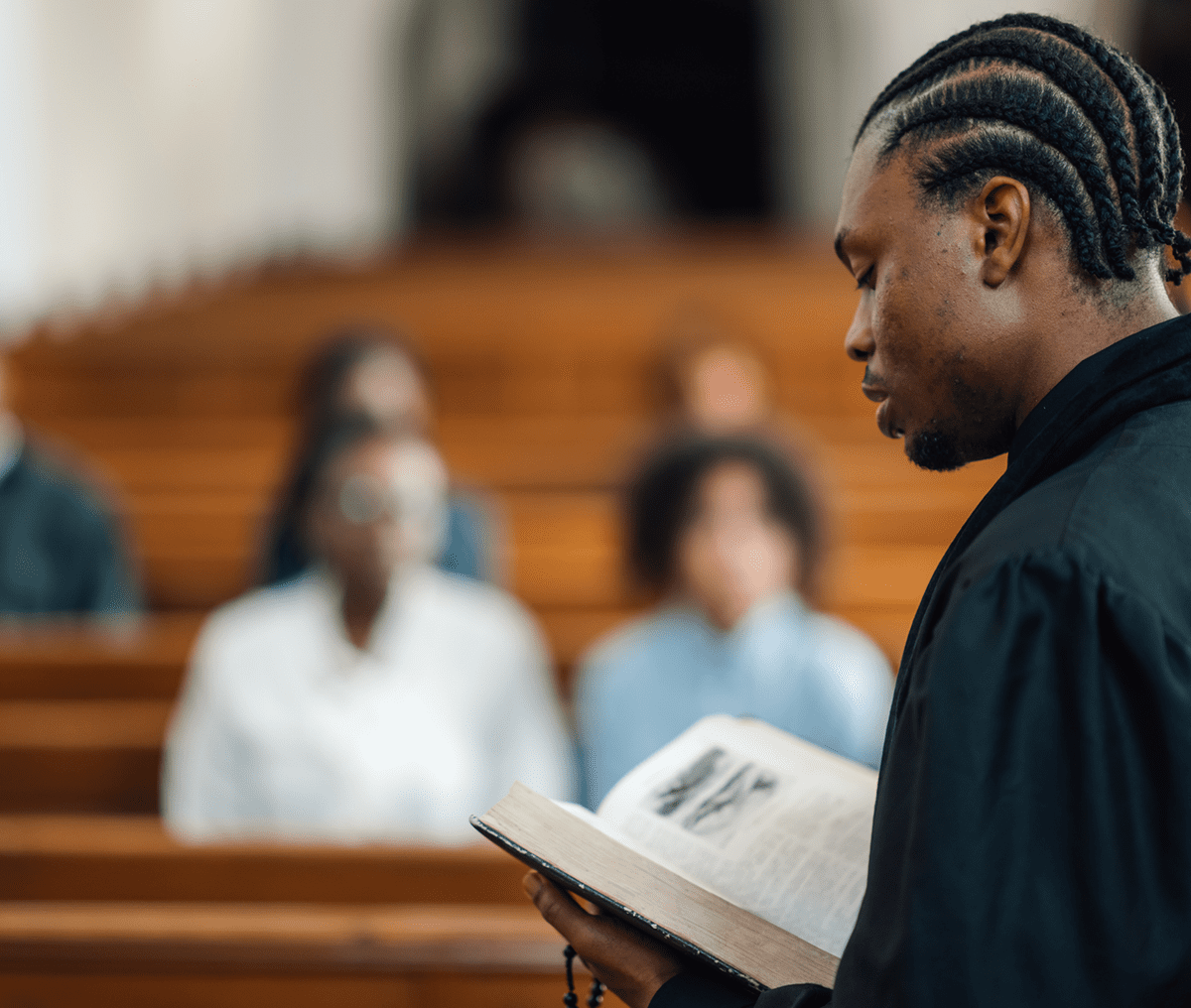 A young man reading from a book in a courtroom.