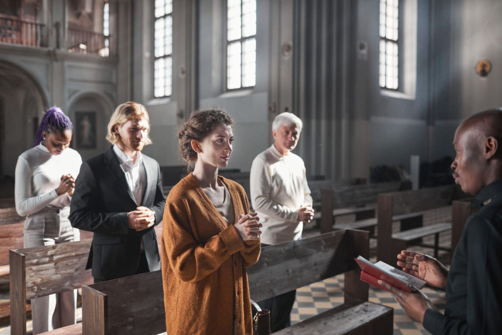 Three people praying inside a church during a service.
