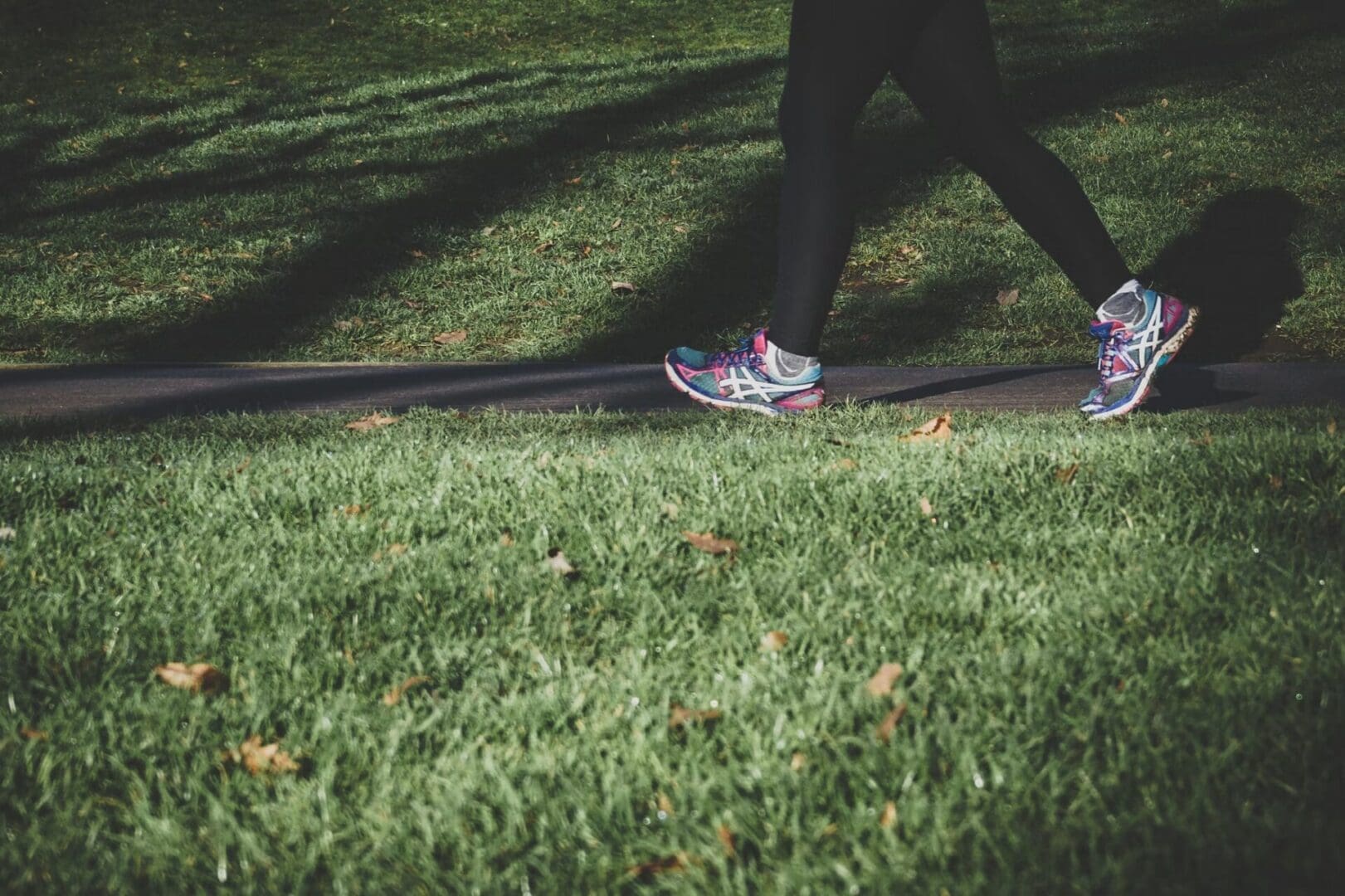 Person walking in leggings beside shaded lawn